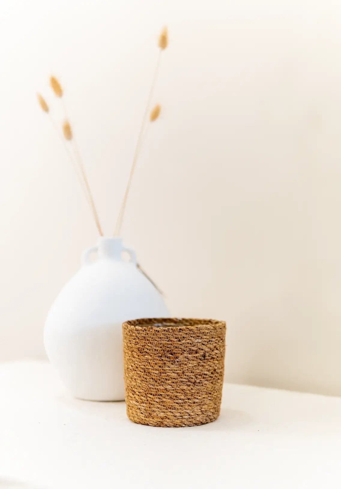 Ceramics Limburg | Sfeerbeeld van de jute bloempot Dove van Ceramics Limburg, gecombineerd met een wit vaasje met naturel droogbloemen | Conceptstore Sisalla